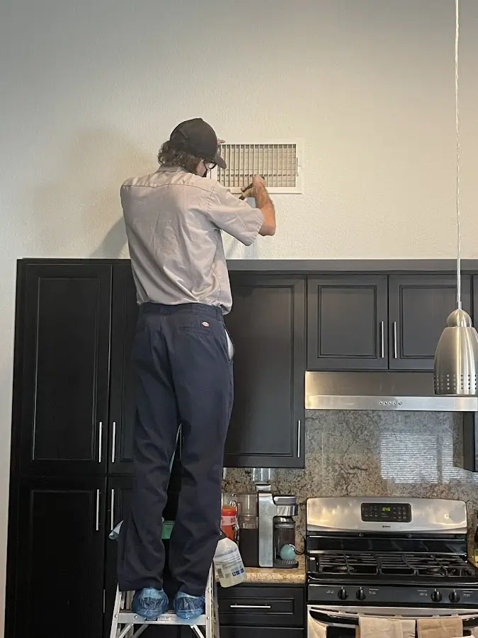 Technician inspecting an air vent during HVAC service in Crockett